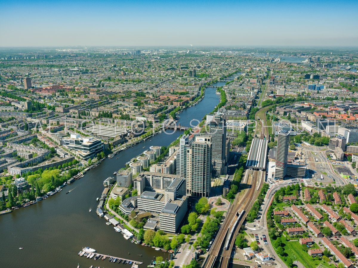 luchtfoto |  Amsterdam,  het Amstelstation met de Rembrandttoren, de Mondriaantoren, de Breitnertoren en de Amsteltower, links van de Omval en de Amstel het kantoorgebouw Rivierstaete. opn. 07/05/2018