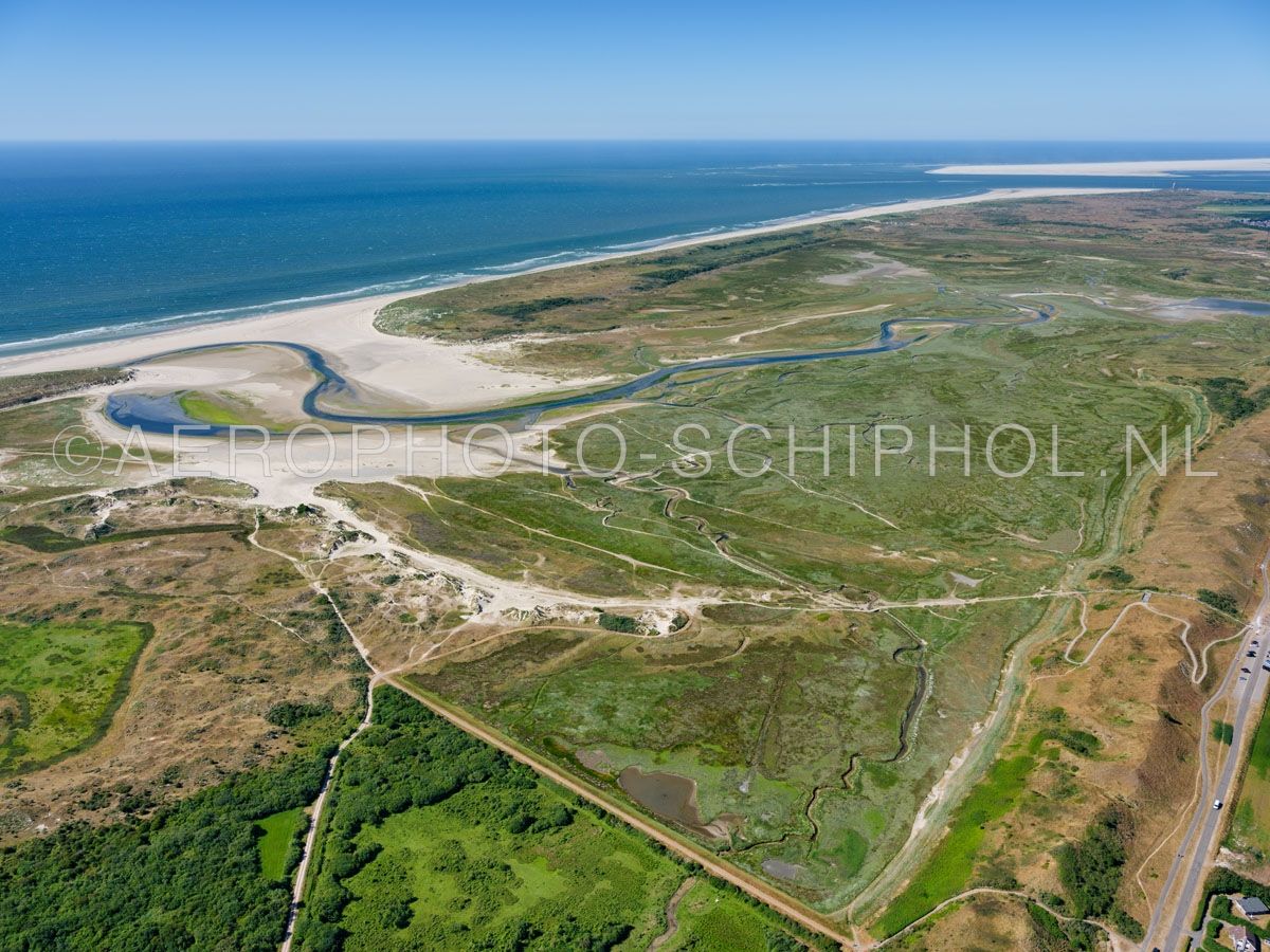 luchtfoto |  Texel, de Slufter mret rechts de Zanddijk. De Slufter is een standvlakte en kwelderlandschap tussen de duinen met een open verbinding naar de Noordzee. opn. 30/06/2018