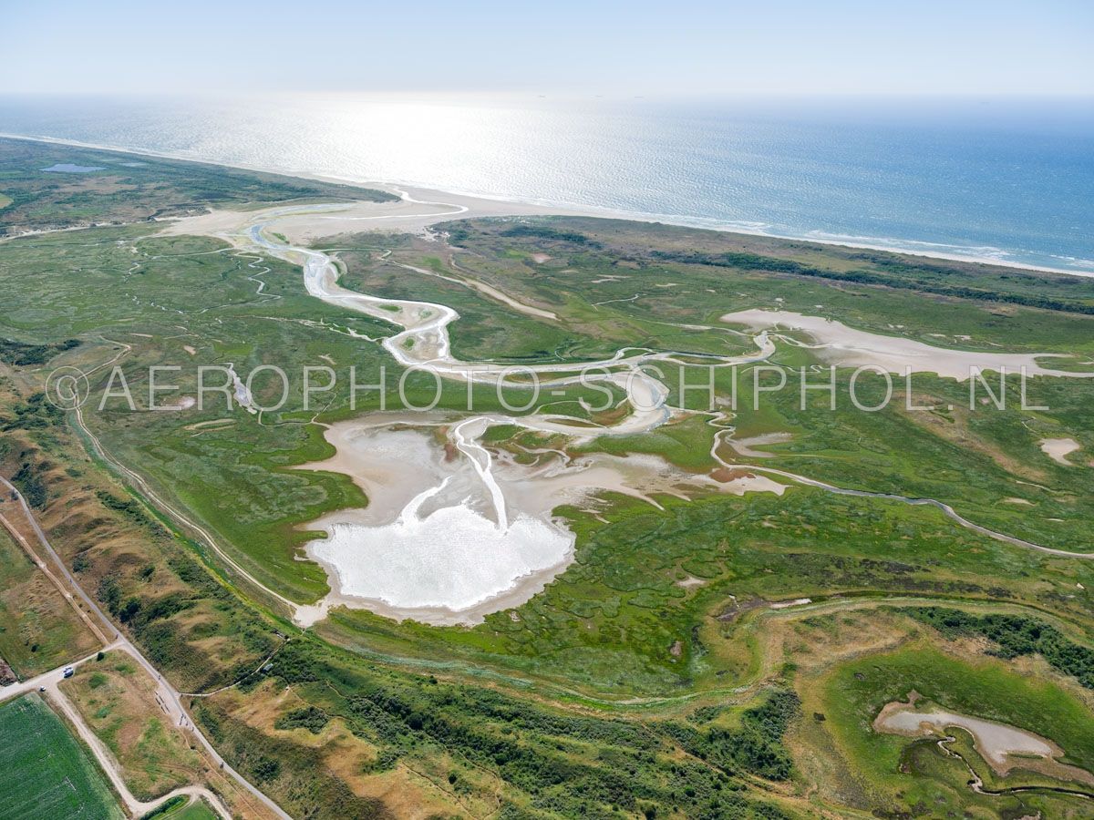 luchtfoto |  Texel, de Slufter en de Noorzeekust gezien vanuit het Noordoosten. De Slufter is een kwelderlandschap, een standvlakte tussen de duinen met een open verbinding naar de Noordzee. opn. 30/06/2018