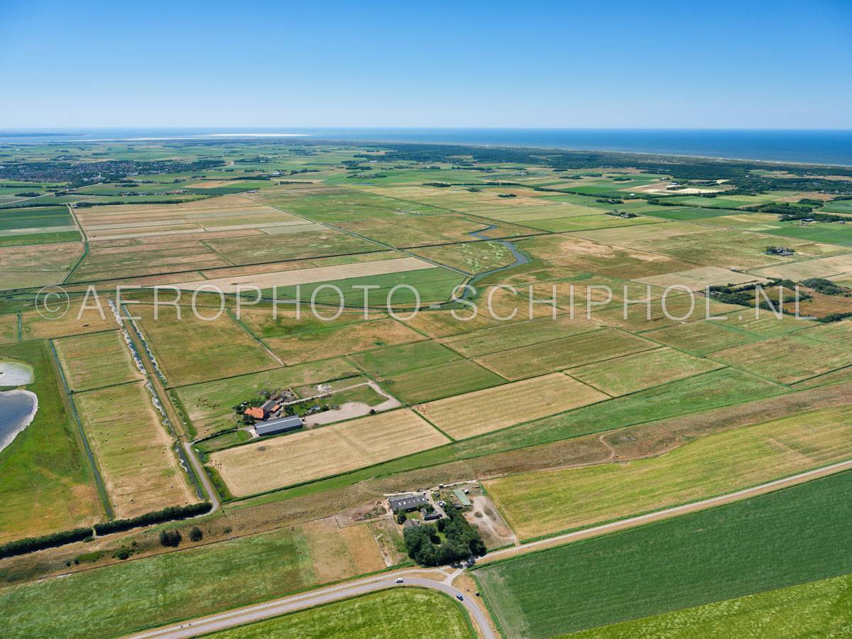 luchtfoto |  Texel, Polder Waal en Burg met in de voorgrond de Ruigendijk. De polder was vroeger een kweldergebied, in het huidige  landschap ligt  nog een oude kreek, deze kreek vind zijn oorsprong in de Westerkolk die is ontstaan bij een doorbraak van de Ruigendijk  | 01/07/2018