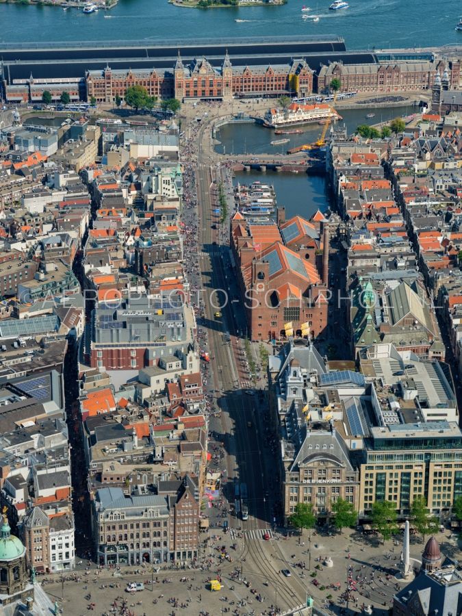luchtfoto |  Amsterdam, Damrak gezien vanaf de Dam met boven in beeld het Amsterdam Centraal Station. Het Damrak was voor het gedempt werd  tussen 1845 en 1883 het stuk van de rivier de Amstel tussen de sluizen op de Dam en het IJ. opn. 02/09/2018