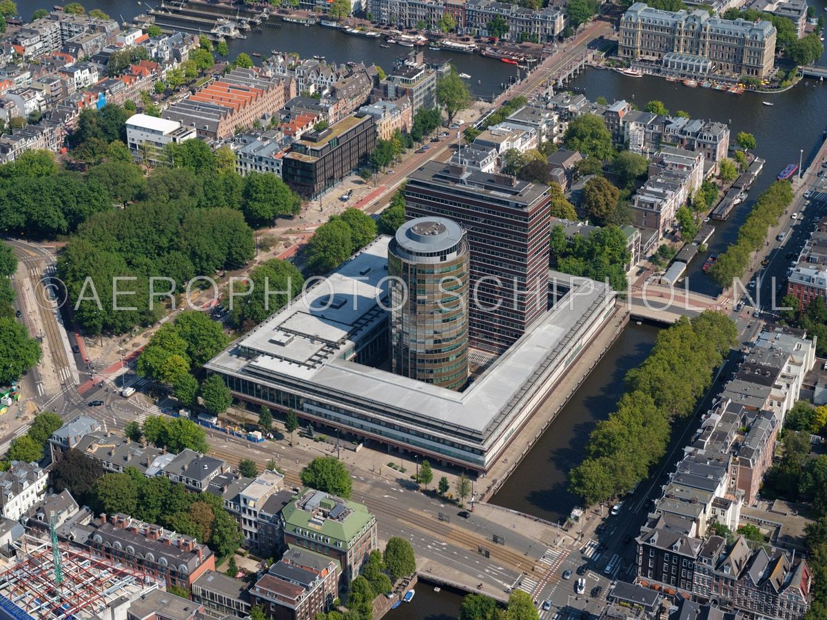 luchtfoto |  Amsterdam, de Nederlandsche Bank (DNB)  is gevestigd aan het Frederiksplein op de plek waar het afgebrande Paleis voor Volksvlijt stond. Het gebouw is ontworpen door  Marius Duintjer in 1961, de uitbreiding in de vorm van de ronde toren, de Satelliet,  is opn. 02/09/2018